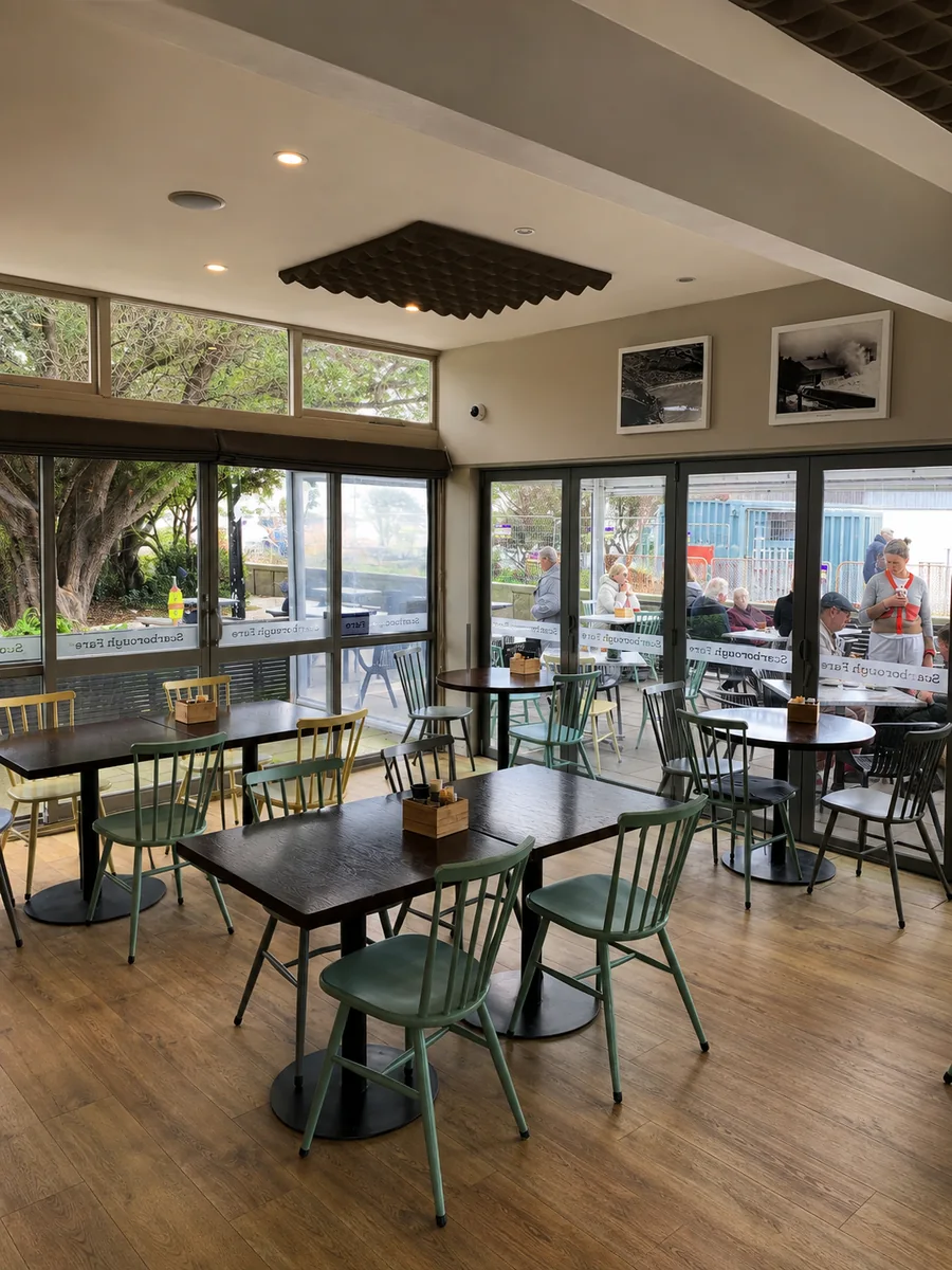 Inside Scarborough Fare with tables and green chairs
