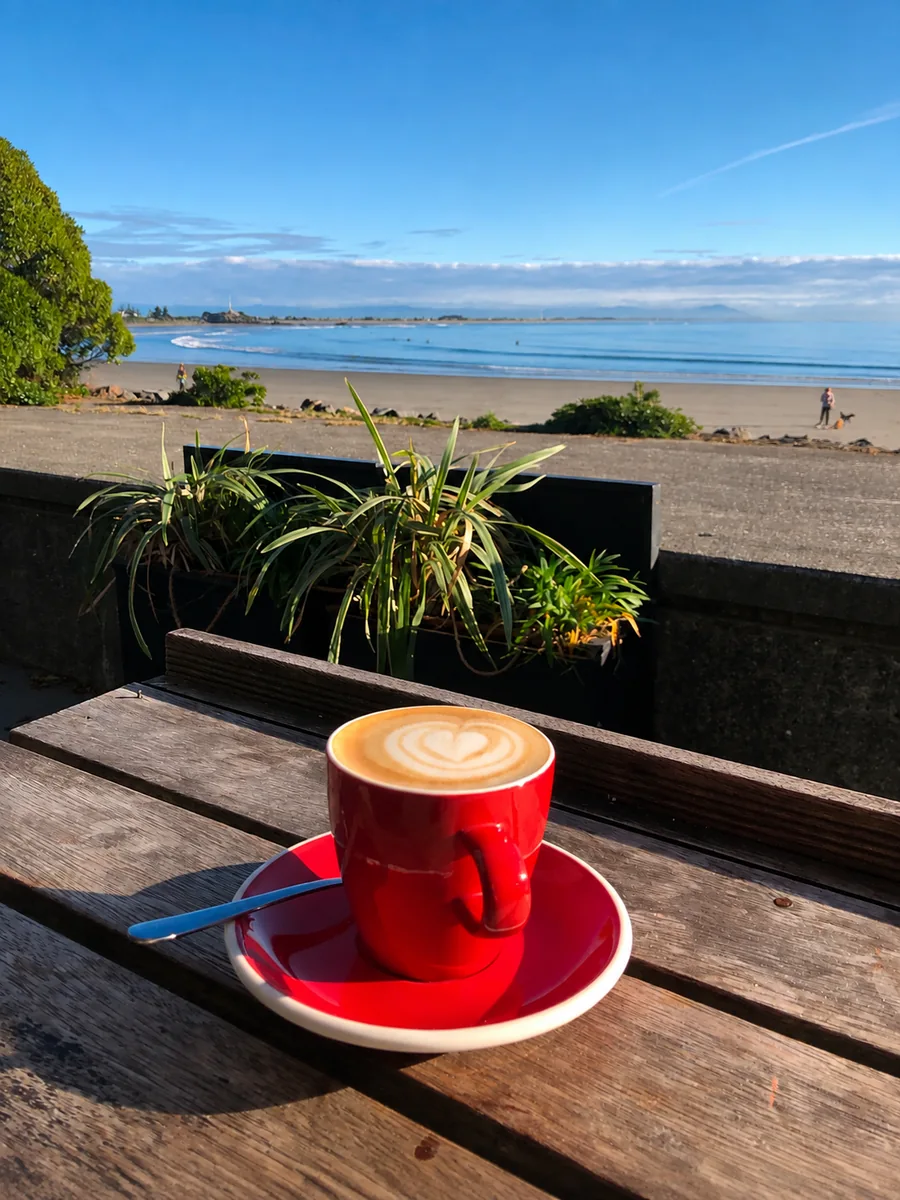 A red cup of coffee on the terrace overlooking the beach